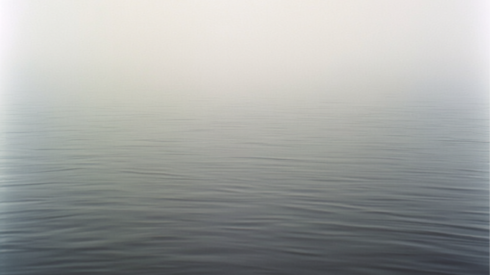 A pale, foggy horizon fading into still water, representing that there's more to reality than my senses can detect.