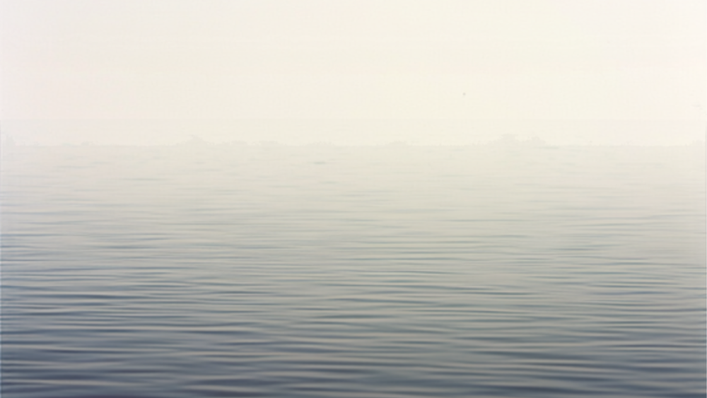 Still, pale water with no reflection of sky, representing why life can feel off even when everything seems fine.